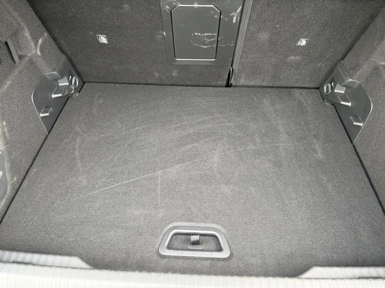 Vue intérieure du coffre spacieux et propre de la Citroën C4 Hybrid 145 gris Mercury, avec tapis de sol noir.