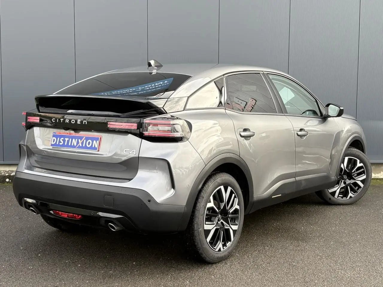 Vue 3/4 arrière droite d'une Citroën C4 gris Mercury avec jantes alliage 18'' et bandeau noir brillant arrière.