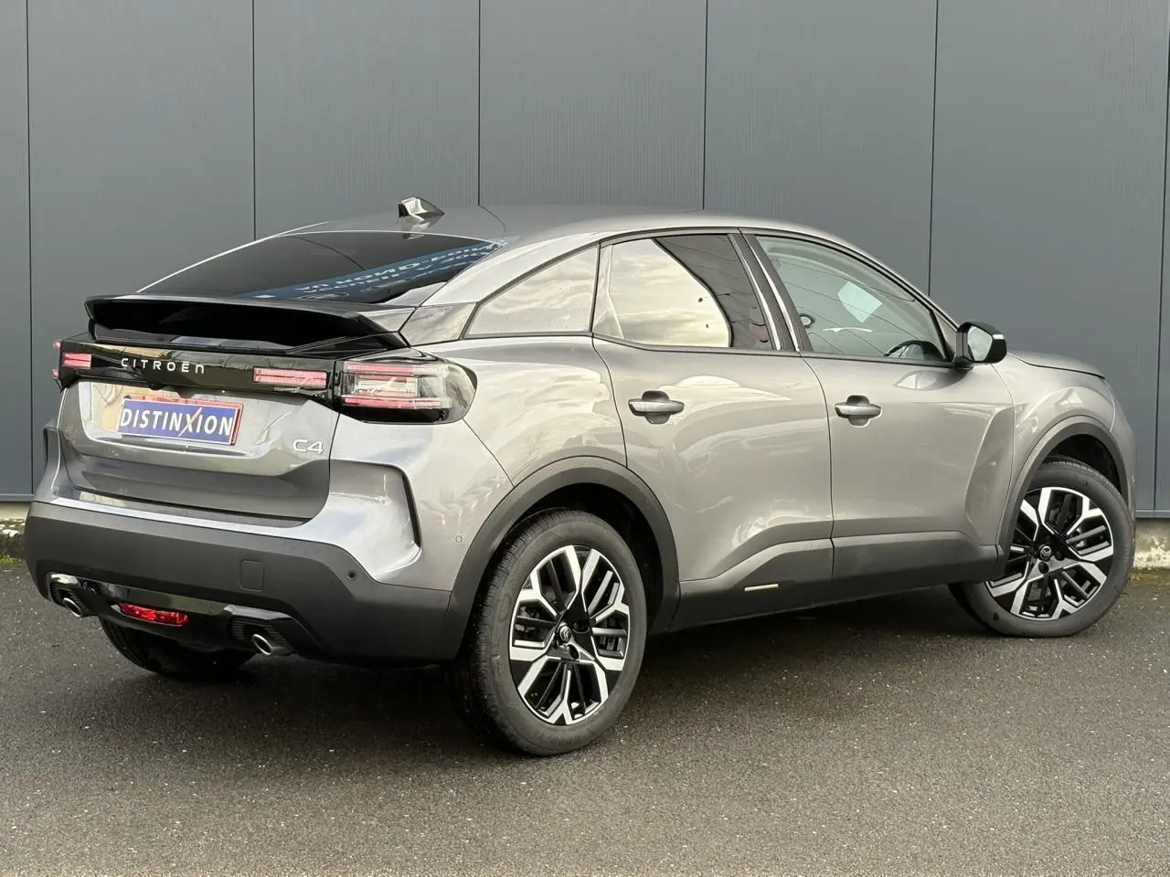 Vue 3/4 arrière droite d'une Citroën C4 gris Mercury avec jantes alliage et toit noir brillant.