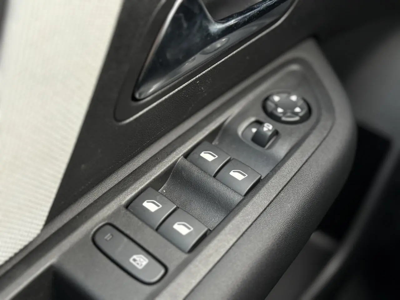 Gros plan sur les commandes des vitres électriques et rétroviseurs côté conducteur d'une Citroën C4 Hybrid gris Mercury.