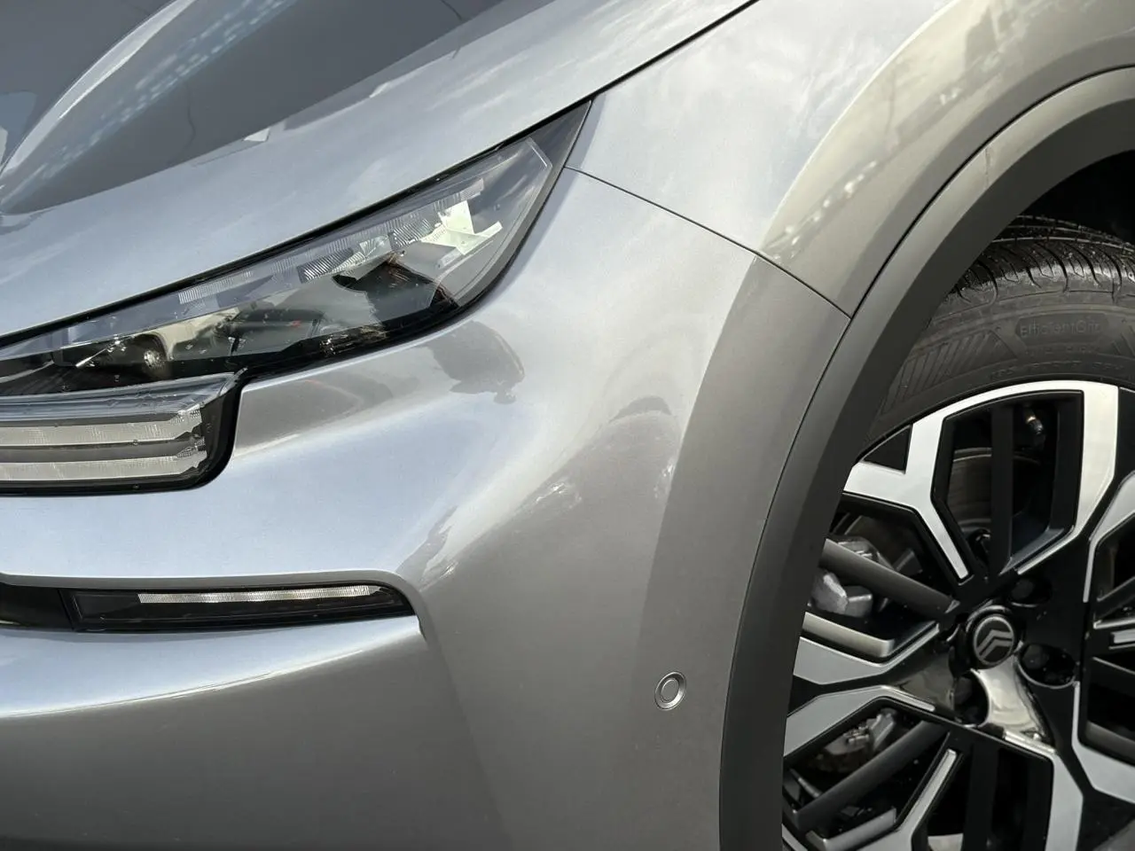 Gros plan sur l'avant droit gris Mercury du Citroën C4 Hybrid 2025 avec phare LED et jante alliage diamantée.