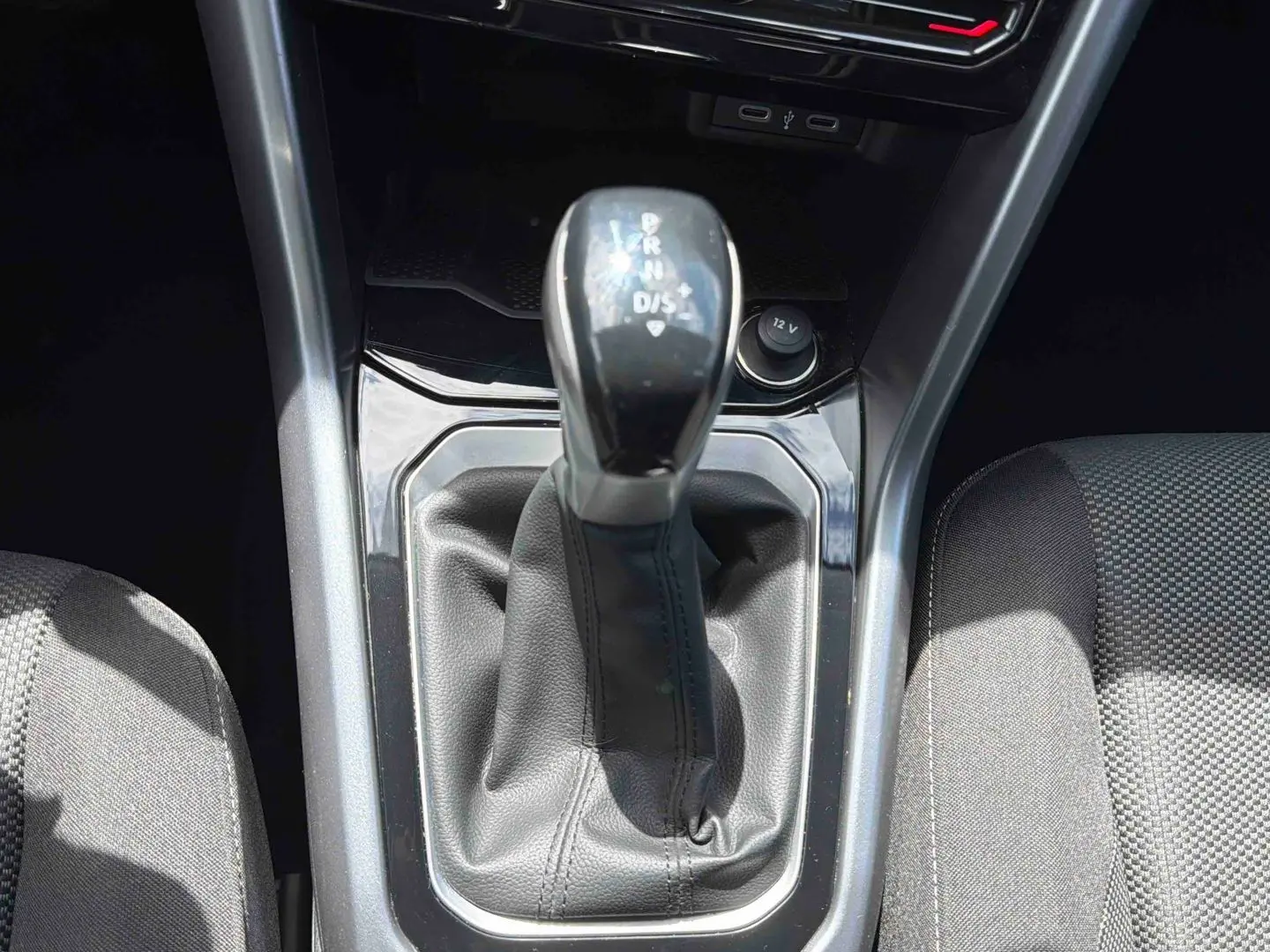 Gros plan sur le levier de vitesse DSG7 noir du Volkswagen T-Roc 2025, entouré de la console centrale et sièges gris.
