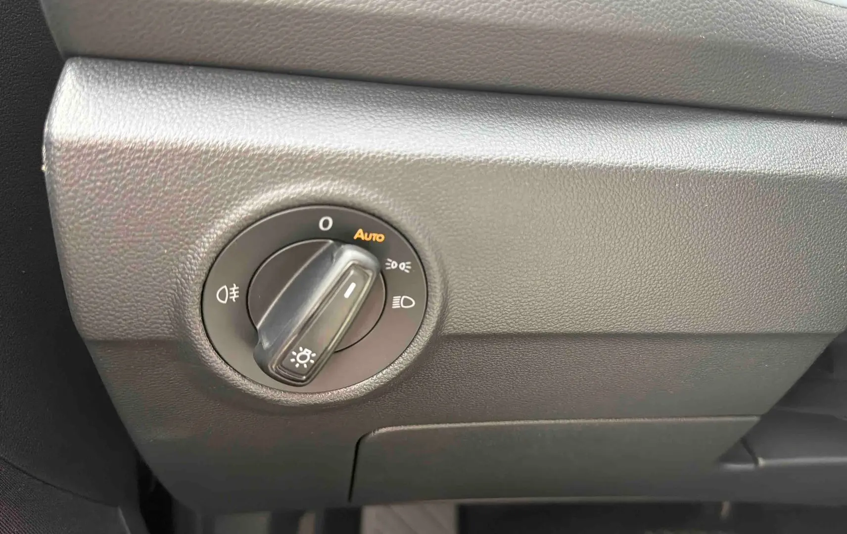 Gros plan sur le bouton de commande des phares du tableau de bord noir du Volkswagen T-Roc 2025.