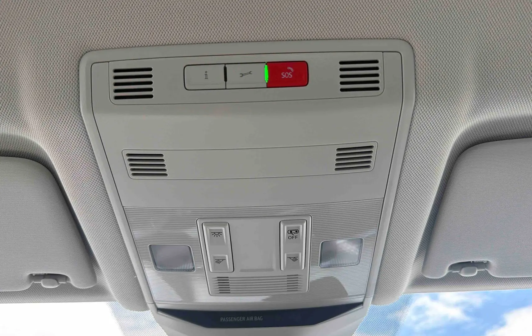 Vue intérieure du plafonnier gris clair avec boutons de commande et alerte SOS allumée dans un Volkswagen T-Roc noir.