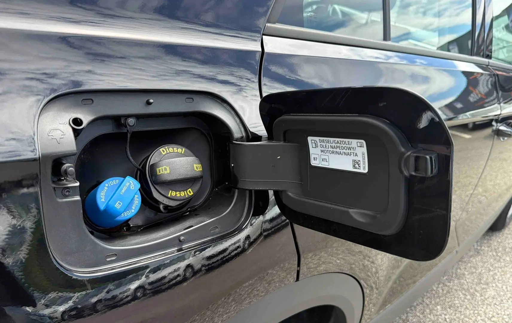 Vue rapprochée de la trappe à carburant ouverte côté gauche d’un Volkswagen T-Roc noir diesel.