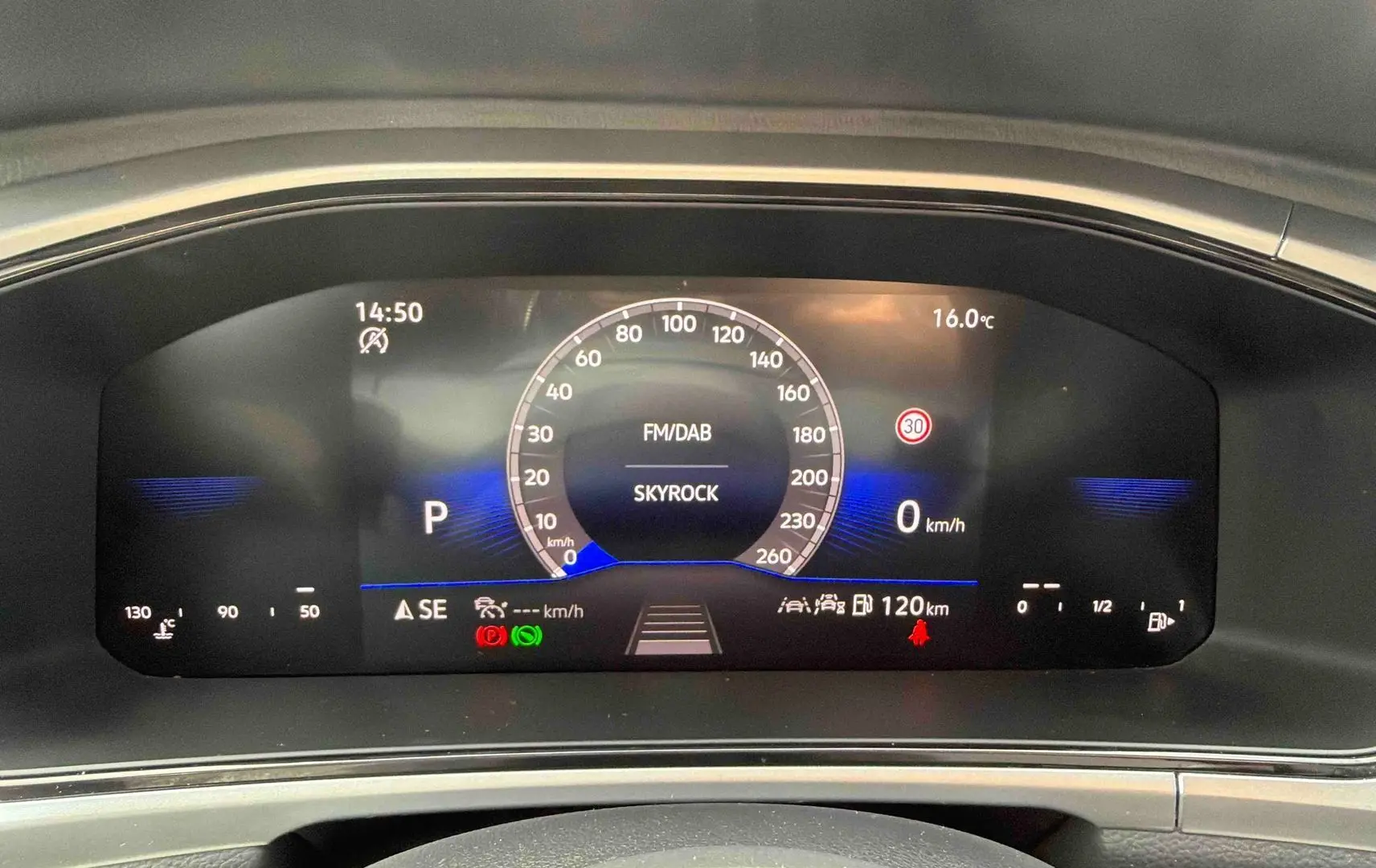 Vue rapprochée du combiné d'instruments digital du Volkswagen T-Roc noir, affichant la vitesse et la radio Skyrock.