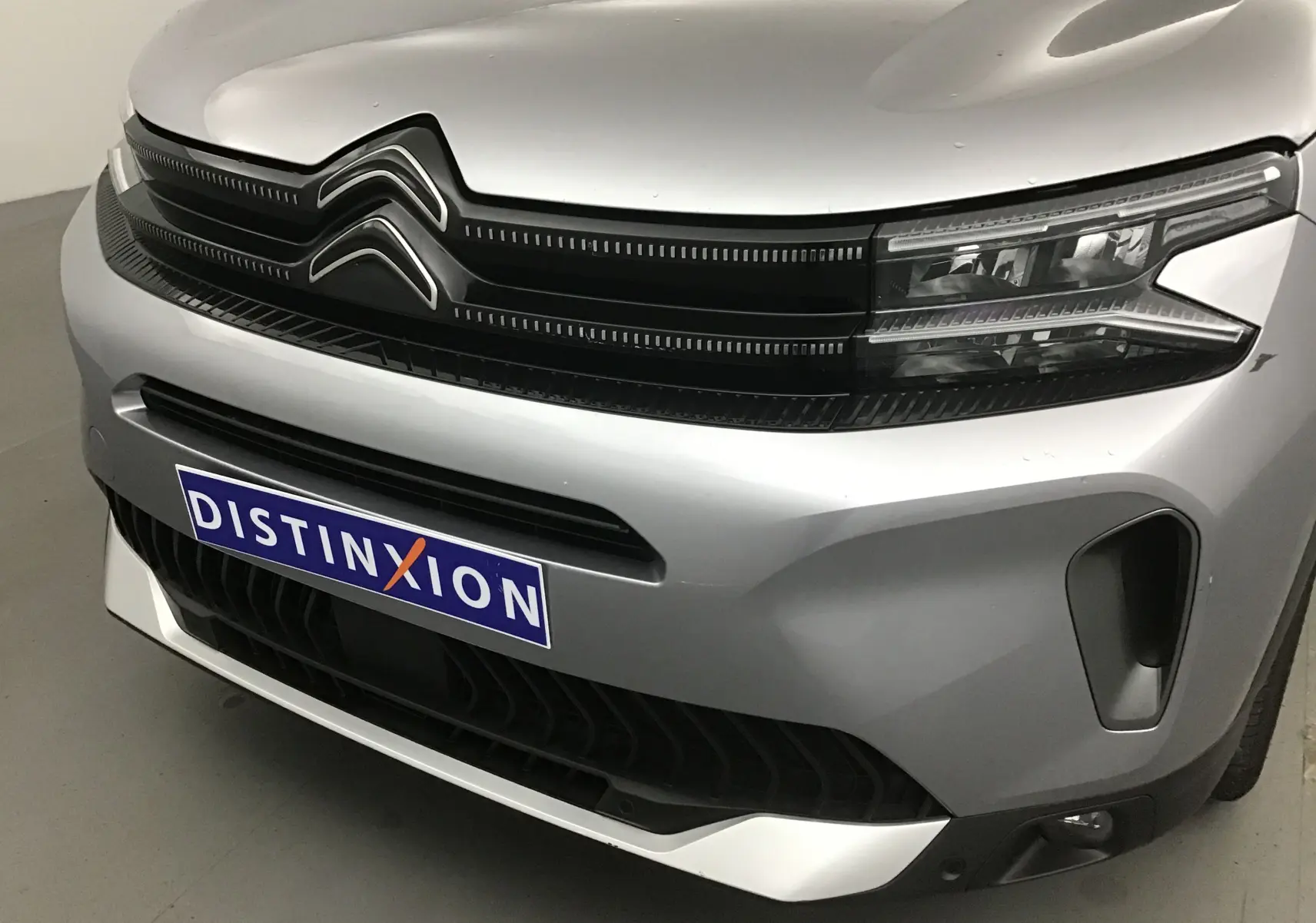 Gros plan sur l'avant gris Artense du Citroën C5 Aircross 2024 avec calandre noire et phares LED distinctifs.