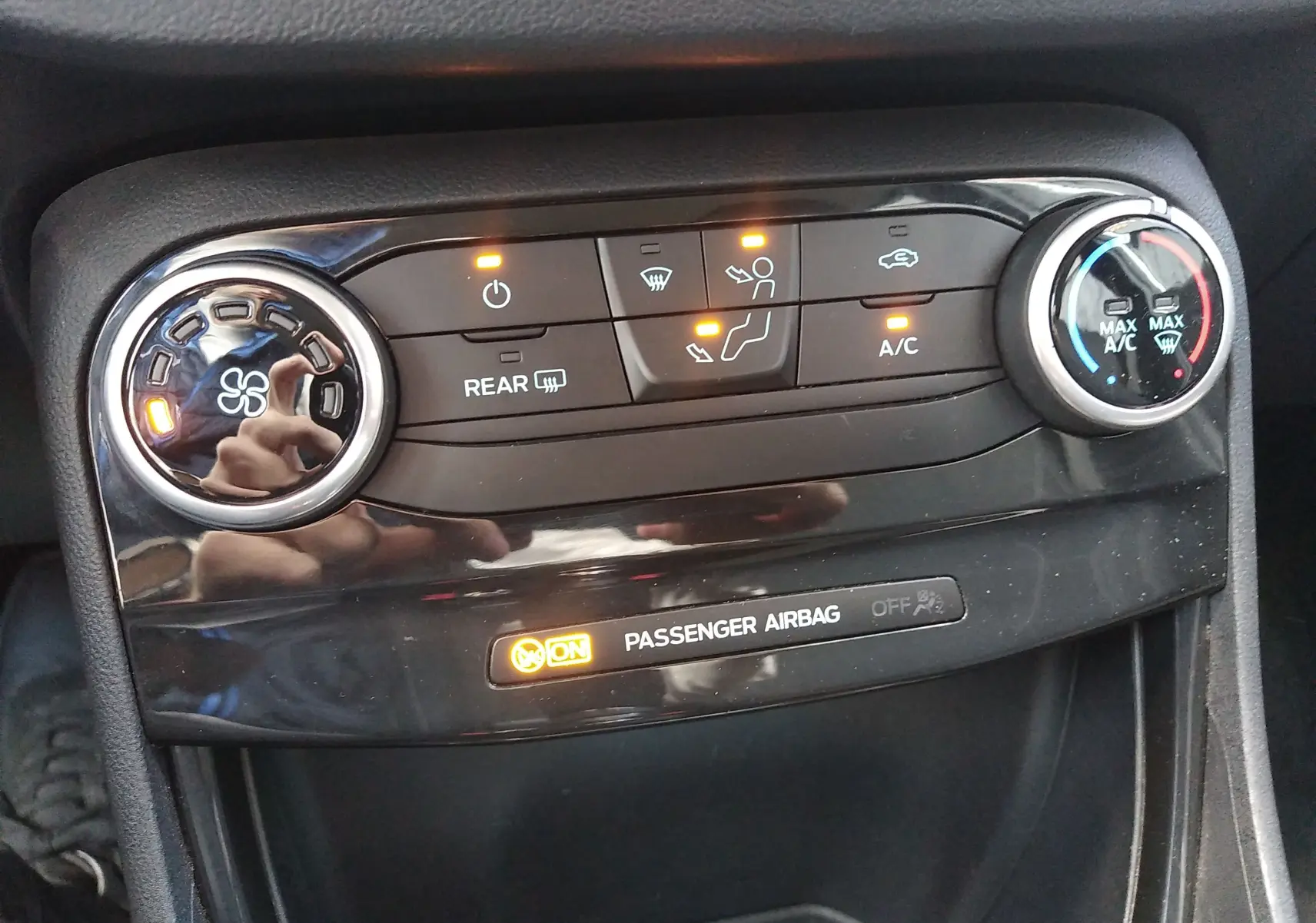 Gros plan sur la console de climatisation du Ford Puma blanc 2021 avec commandes et témoin airbag passager allumé.