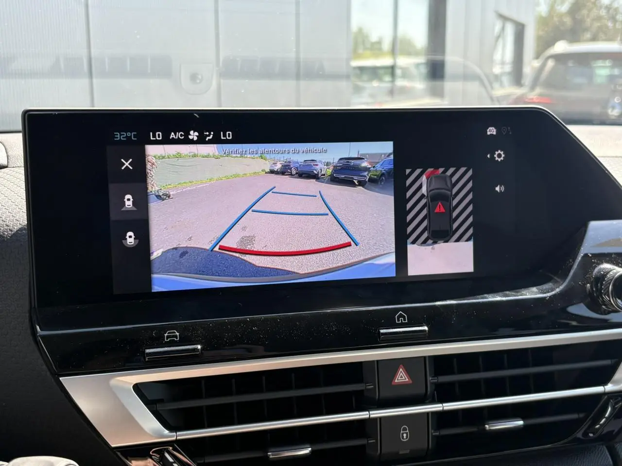 Écran tactile intérieur montrant la caméra de recul avec vue arrière et alertes de stationnement du Citroën C4 Hybrid blanc.
