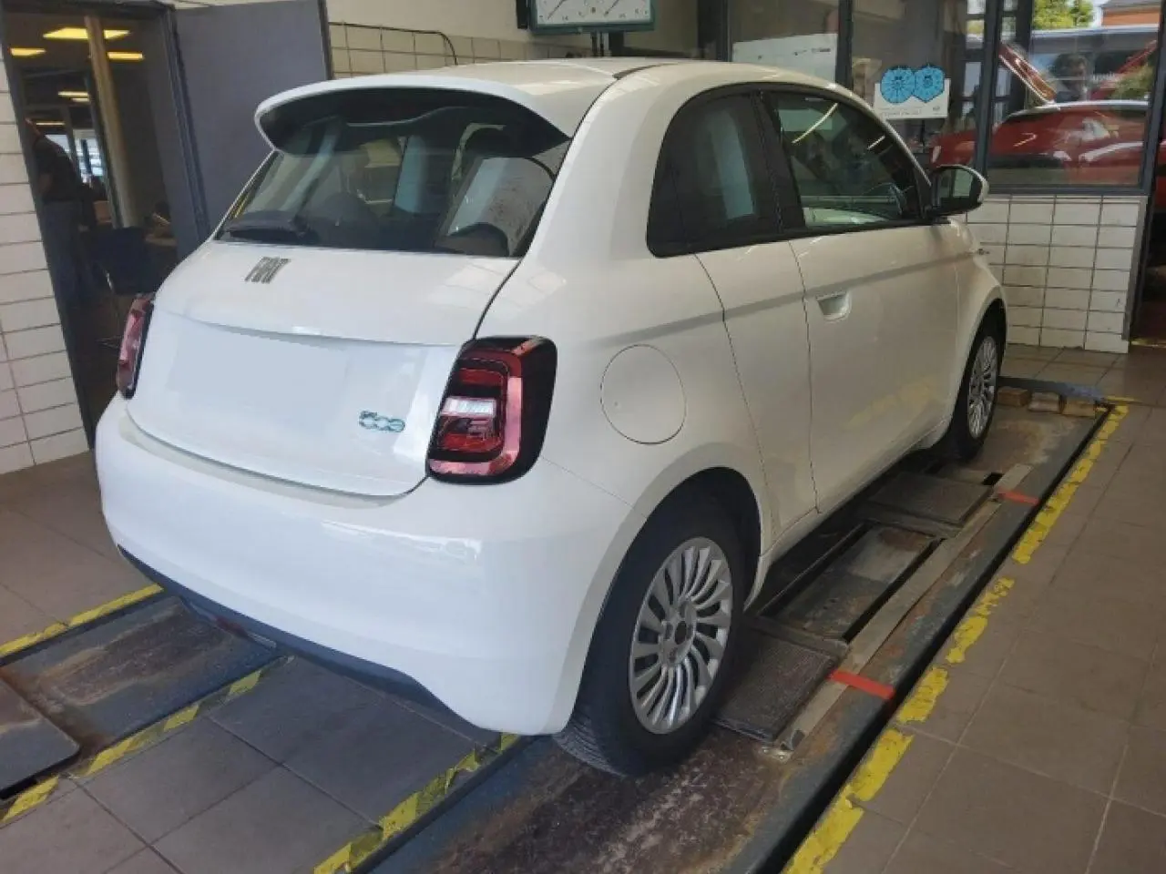 Vue 3/4 arrière droite d'une Fiat 500 électrique blanche 2024, avec feux arrière LED et jantes spécifiques Icone.