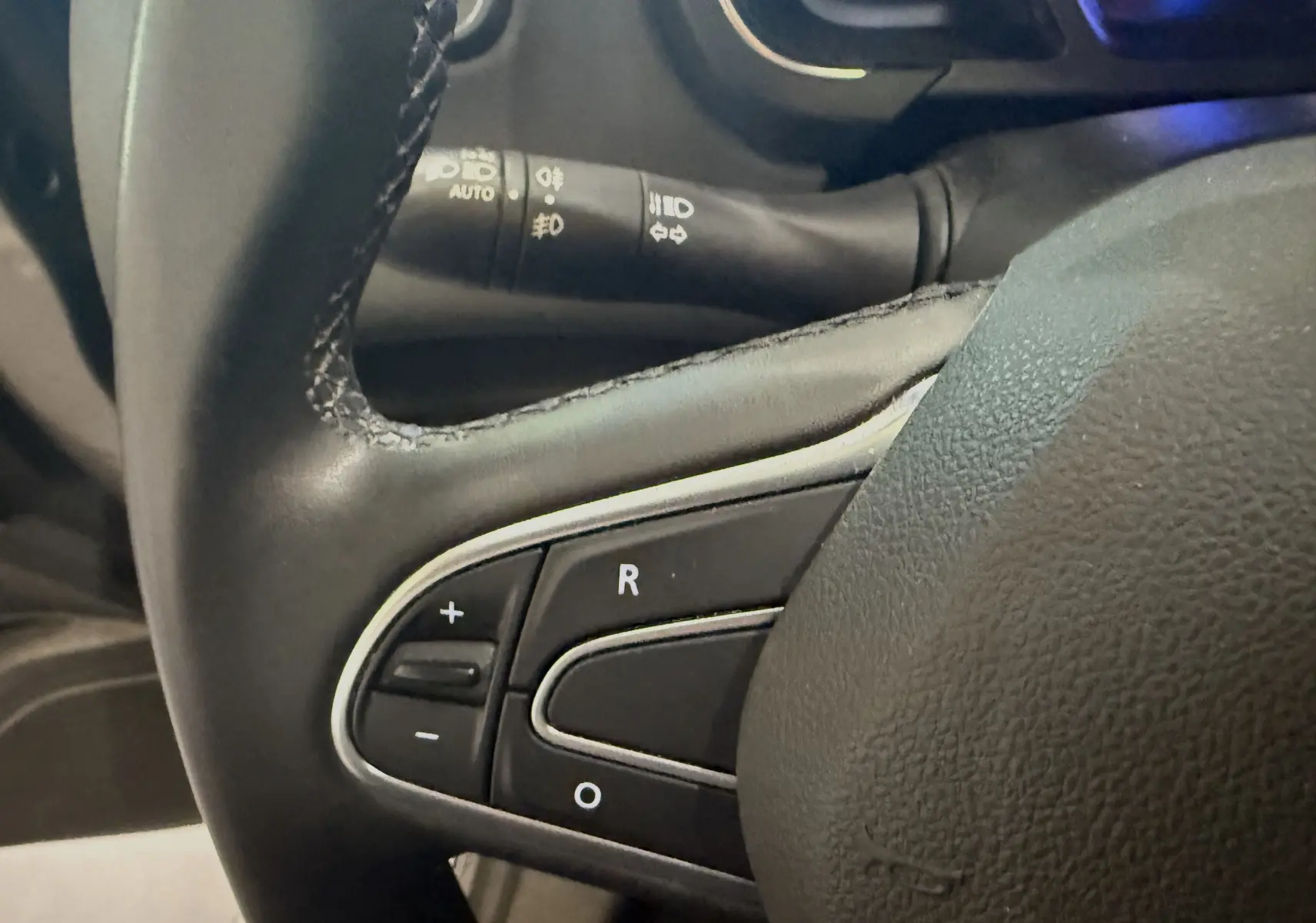 Gros plan sur les commandes de régulateur de vitesse au volant cuir noir du Renault Grand Scenic IV Business gris Cassiopée.