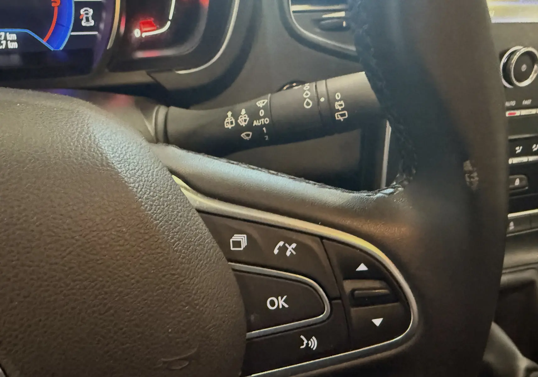 Gros plan sur le volant noir du Renault Grand Scenic IV Business avec commandes intégrées et tableau de bord partiellement visible.