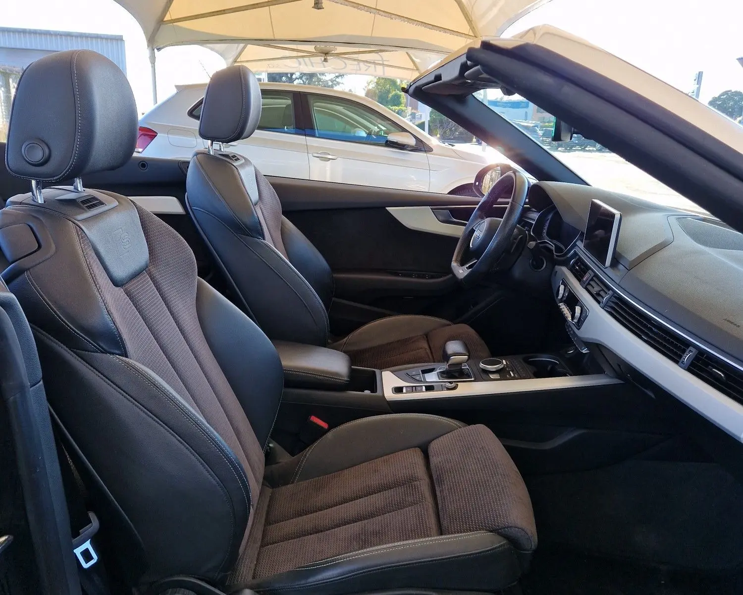 Intérieur noir de l'Audi A5 Cabriolet 2017 vu côté gauche, sièges sport en cuir et tissu avec tableau de bord moderne.