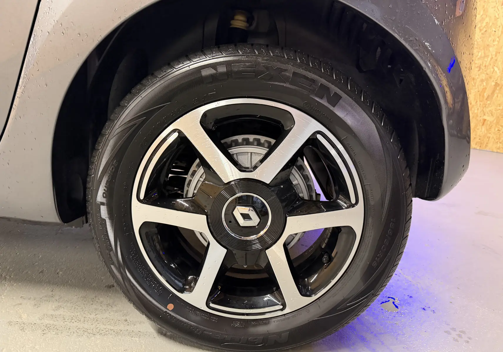 Gros plan sur la roue avant droite d’une Renault Twingo III gris, avec jante alliage bicolore et logo Renault central.