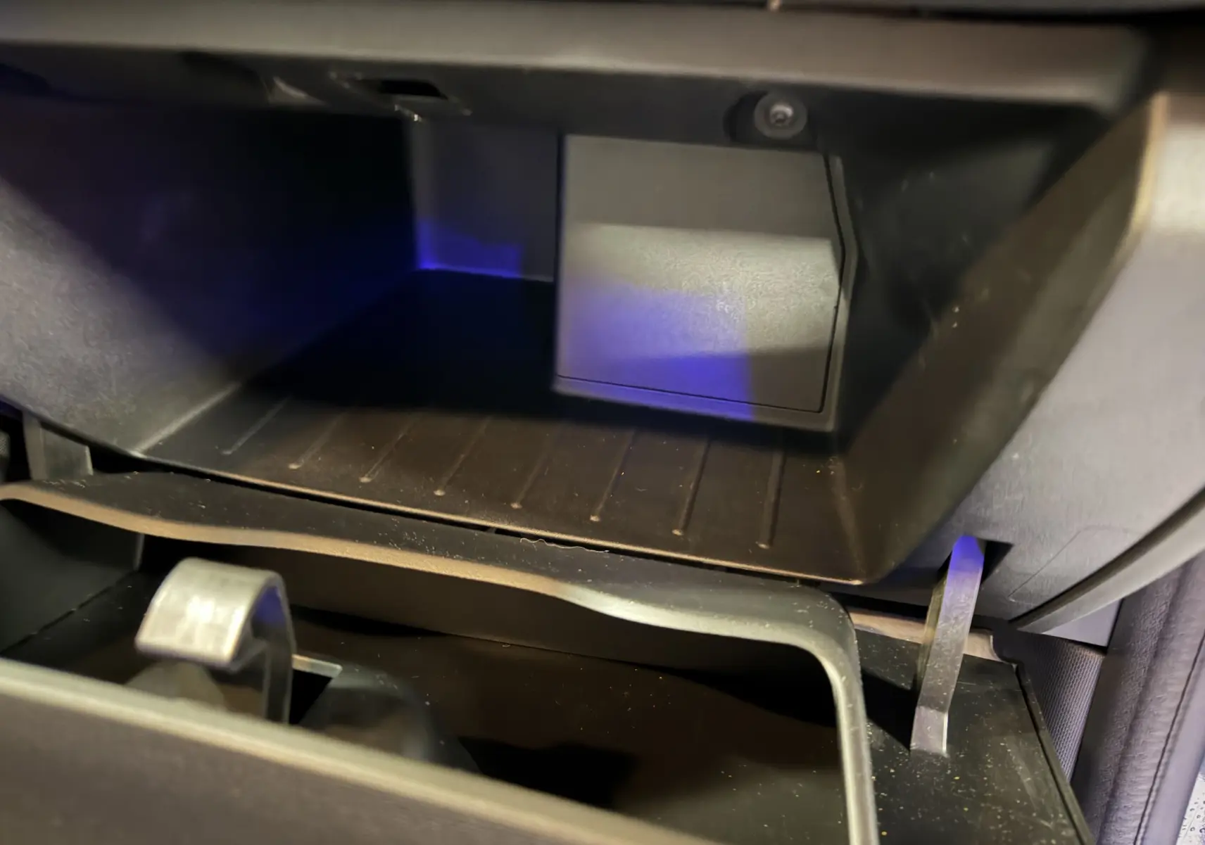 Vue rapprochée de la boîte à gants ouverte de la Renault Twingo III gris, montrant l'intérieur en plastique noir.