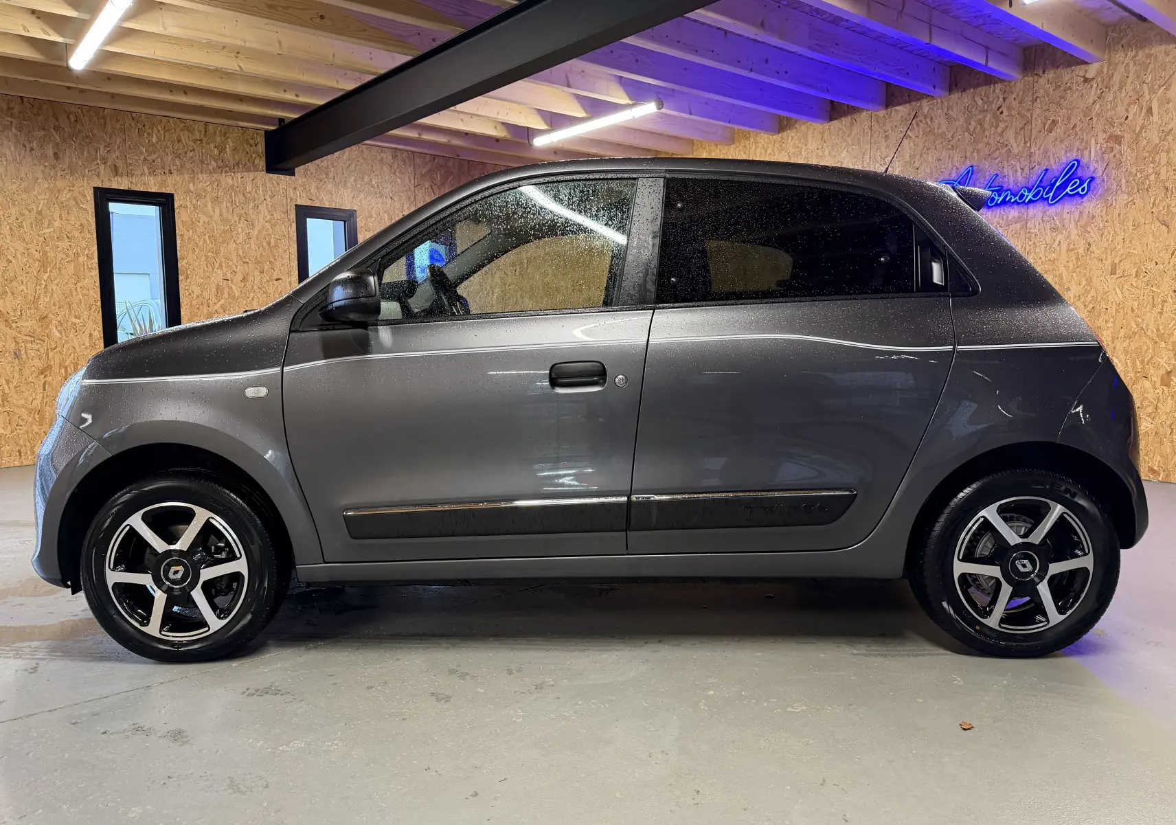 Profil droit d'une Renault Twingo III gris métallisé 2018, avec jantes noires et détails noirs sur les portières.
