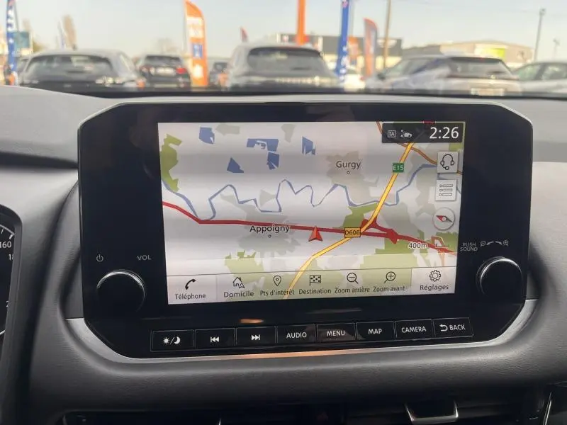 Écran tactile central du Nissan Qashqai 2022 affichant la navigation GPS avec carte et commandes audio visibles.