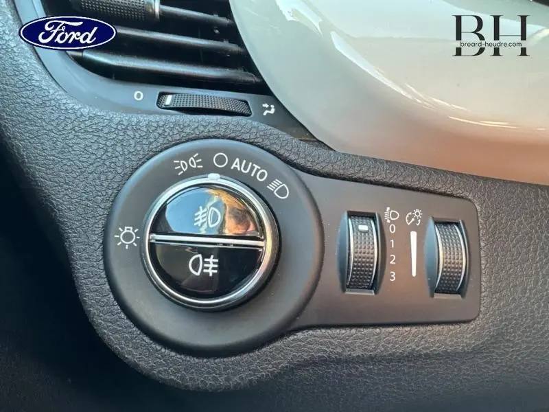Gros plan sur le bouton de commande des phares d’un Fiat 500X argenté, avec réglages d’éclairage et tableau de bord noir.