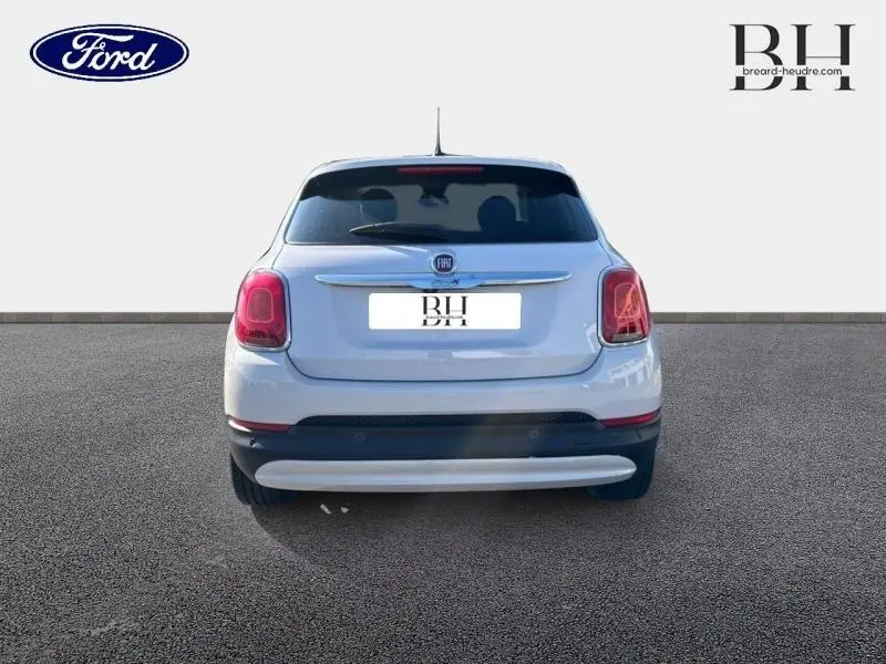 Vue arrière d'une FIAT 500X argentée de 2015 avec feux rouges et lunette arrière surteintée sur fond neutre.