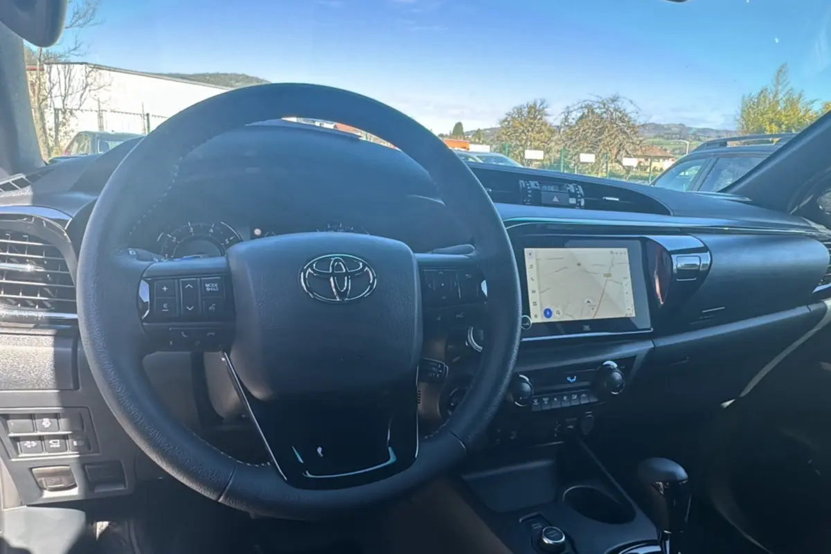 Vue intérieure centrée sur le volant cuir multifonctions et l'écran tactile du tableau de bord du Toyota Hilux 2026.