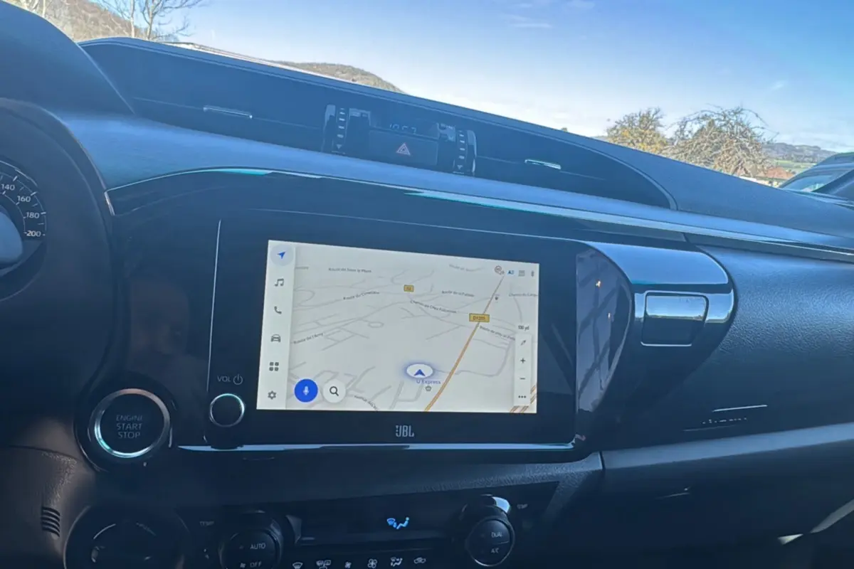 Vue intérieure du tableau de bord du Toyota Hilux 2026, écran tactile GPS 8 pouces et bouton start/stop visibles.
