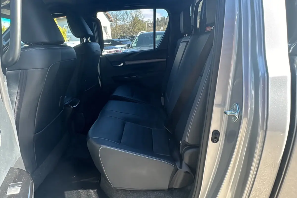 Vue intérieure arrière côté droit du Toyota Hilux 4x4 gris acier, montrant les sièges arrière en cuir noir.