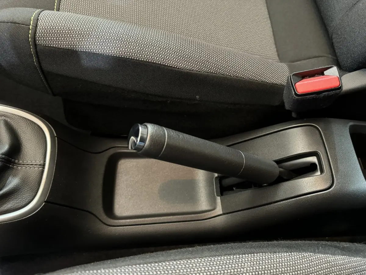 Vue rapprochée de la poignée de frein à main noire et du siège tissu gris dans une Citroën C3 2020.