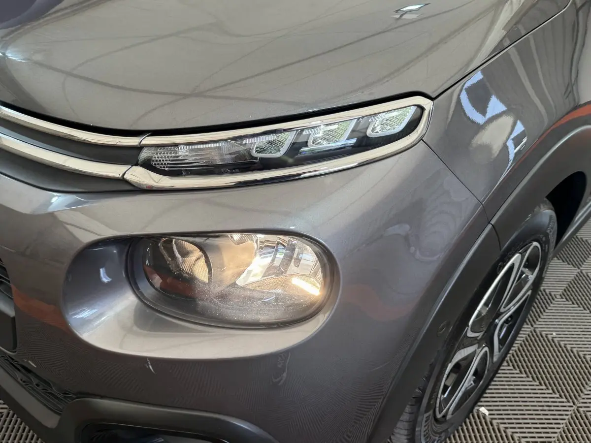Gros plan sur l’avant droit gris foncé de la Citroën C3 2020, mettant en valeur ses phares LED et sa jante au design distinctif.
