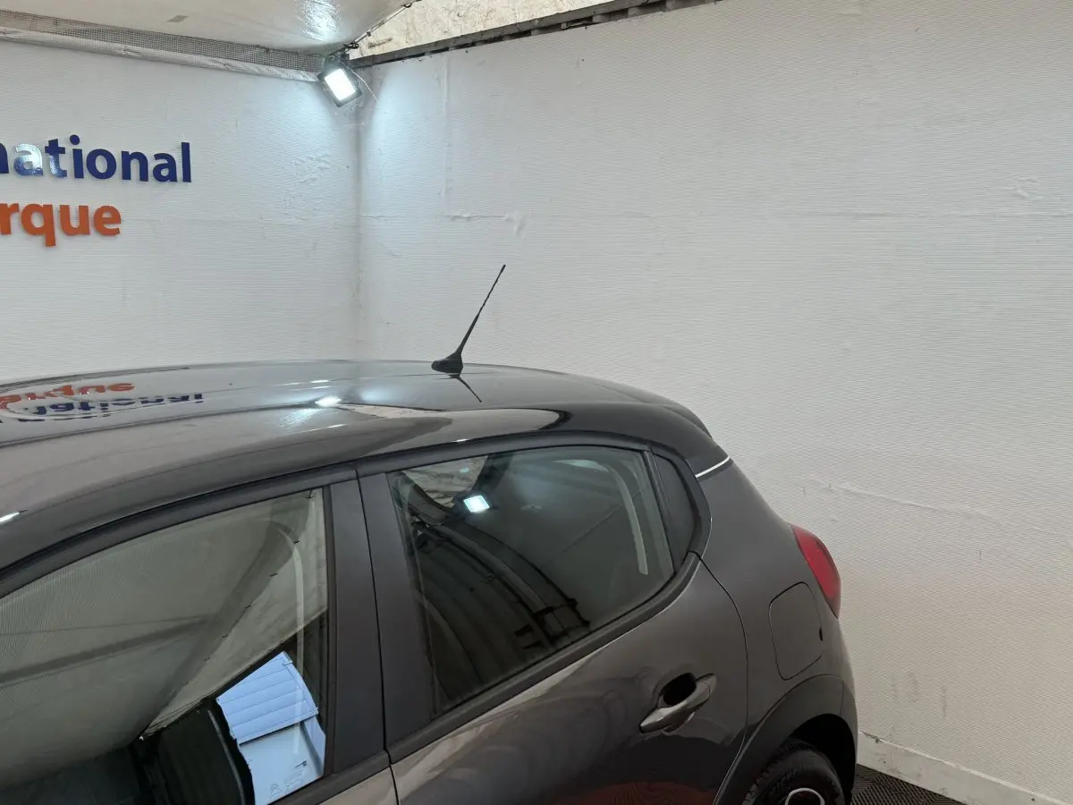 Vue côté droit arrière d'une Citroën C3 gris foncé, montrant la porte arrière et l'antenne de toit.