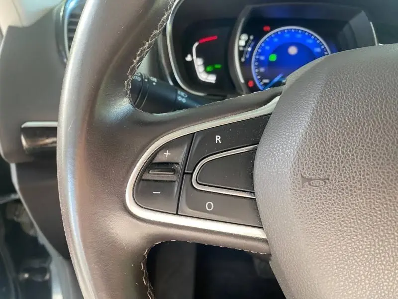 Gros plan sur le volant cuir noir du Renault Espace V 2018 avec commandes intégrées et tableau de bord bleu en arrière-plan.