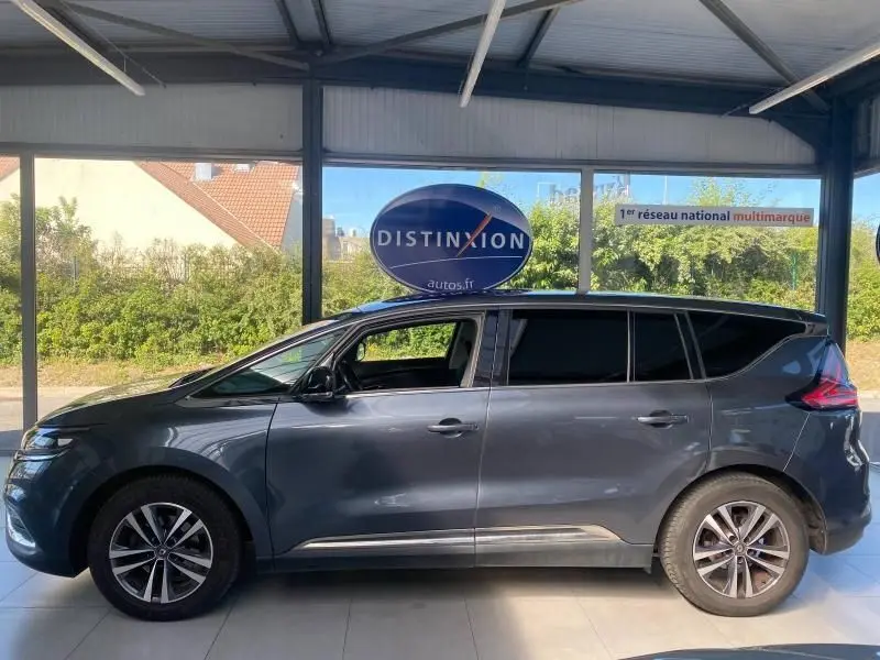 Profil côté gauche d'un Renault Espace V gris exposé en intérieur avec vitres arrière surteintées et jantes alliage.