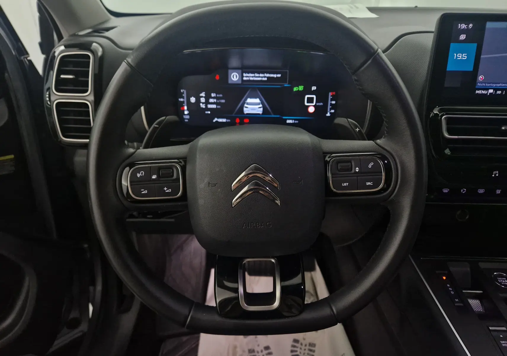 Vue centrée du volant cuir noir du Citroën C5 Aircross 2024 avec tableau de bord numérique et écran tactile.