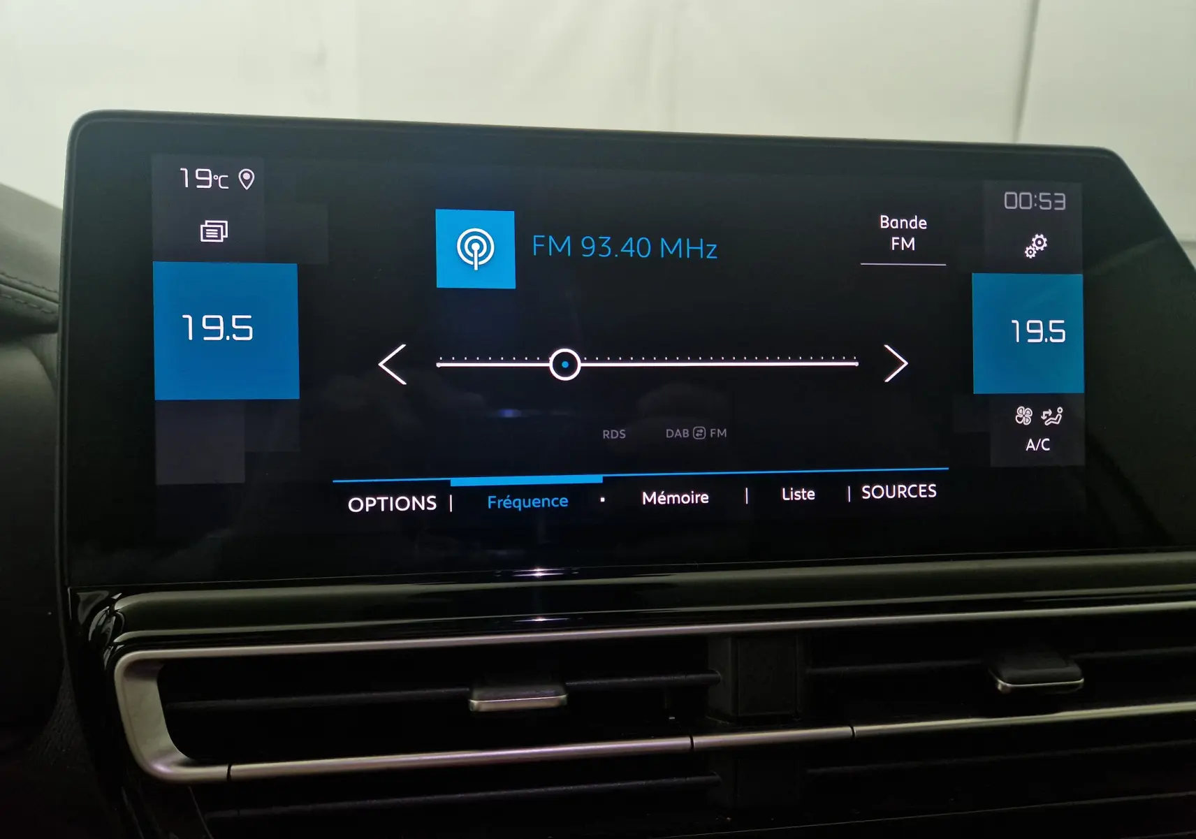 Écran tactile central du tableau de bord du Citroën C5 Aircross 2024 affichant la radio FM et la climatisation à 19,5°C.