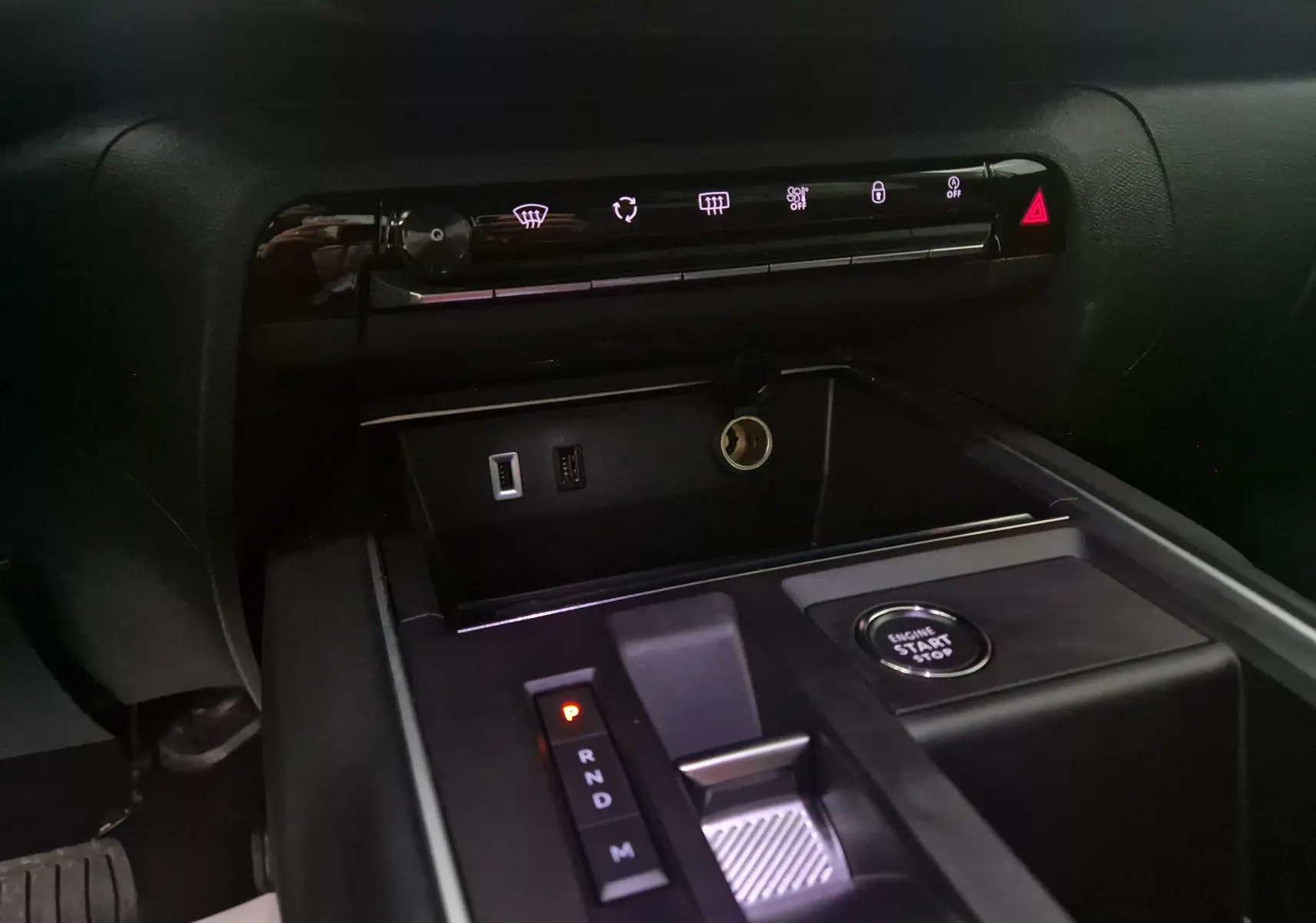 Gros plan sur la console centrale noire du Citroën C5 Aircross 2024, avec bouton start, levier de vitesses et commandes éclairées.