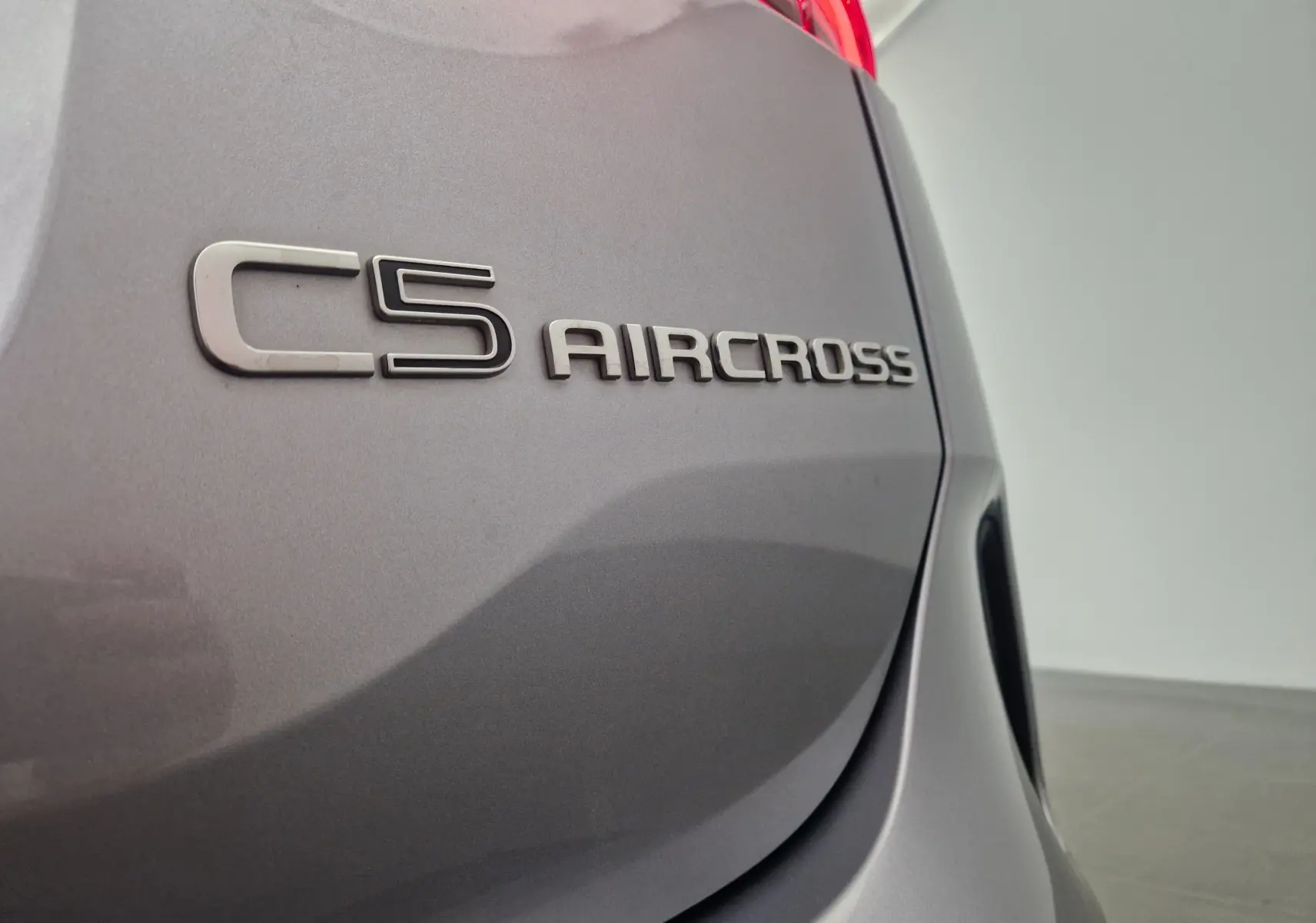 Gros plan sur l'arrière droit gris Artense d'un Citroën C5 Aircross 2024, mettant en valeur le logo du modèle.
