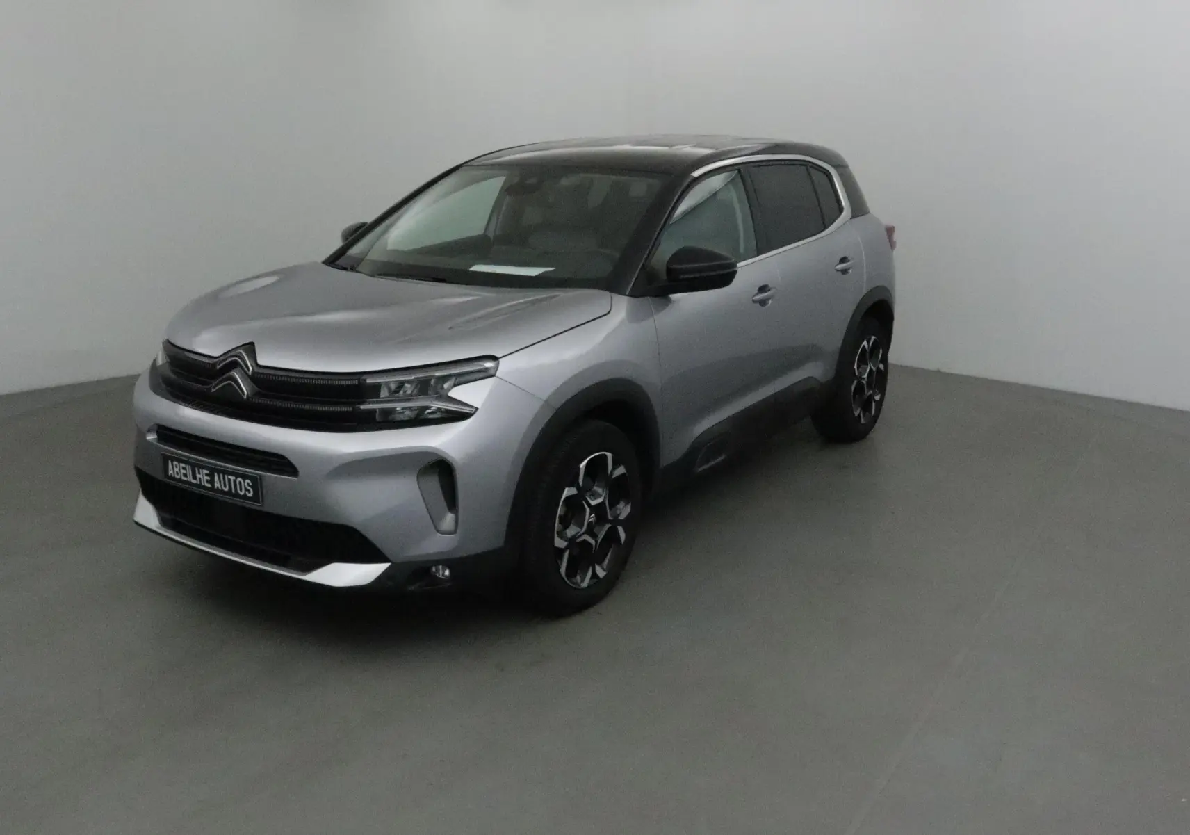 Citroën C5 Aircross 2024 gris Artense avec toit noir, vue 3/4 avant droit en intérieur neutre.