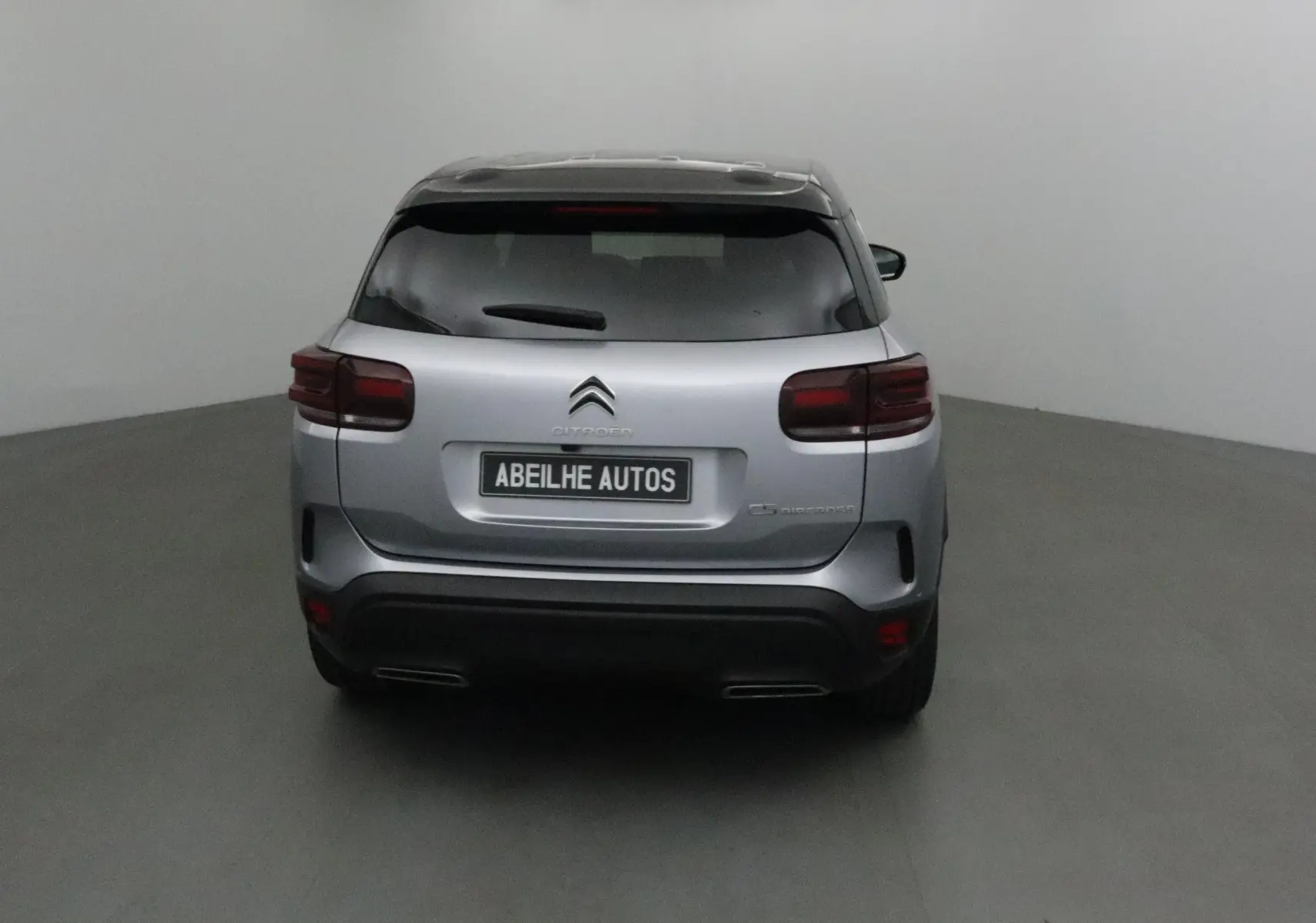 Vue arrière d'un Citroën C5 Aircross gris Artense avec toit noir, feux arrière foncés et double sortie d'échappement.