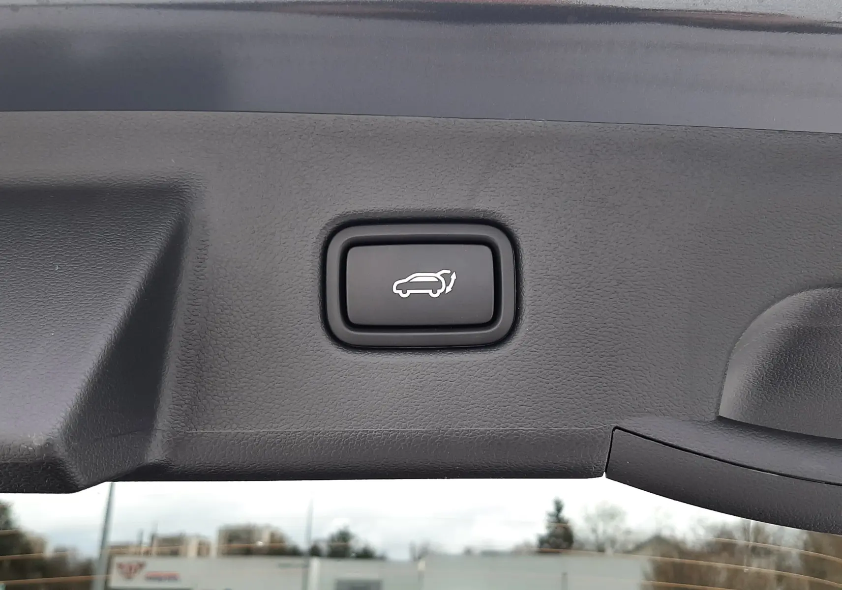 Gros plan sur le bouton d'ouverture électrique du hayon du Hyundai Tucson 2025 en gris Ecotronic.