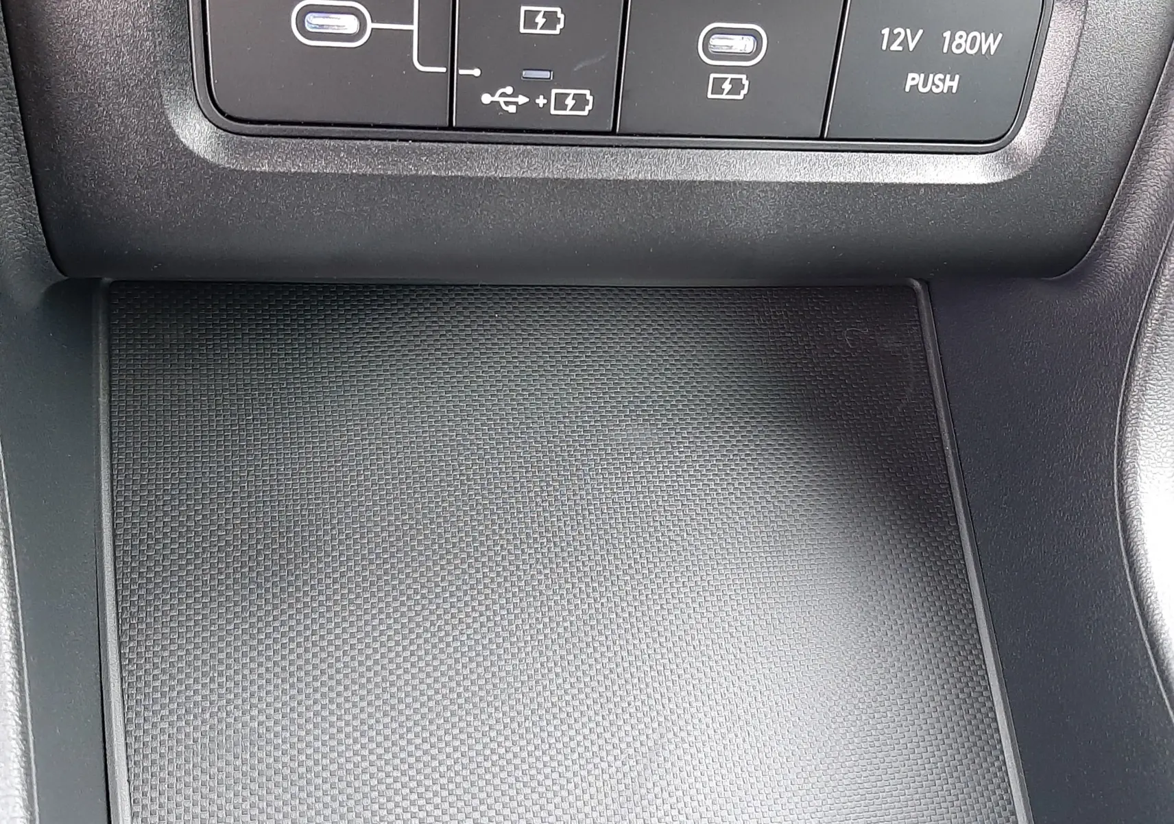 Détail de la console centrale du Hyundai Tucson 2025 avec prises USB, charge sans fil et prise 12V, finition noire.