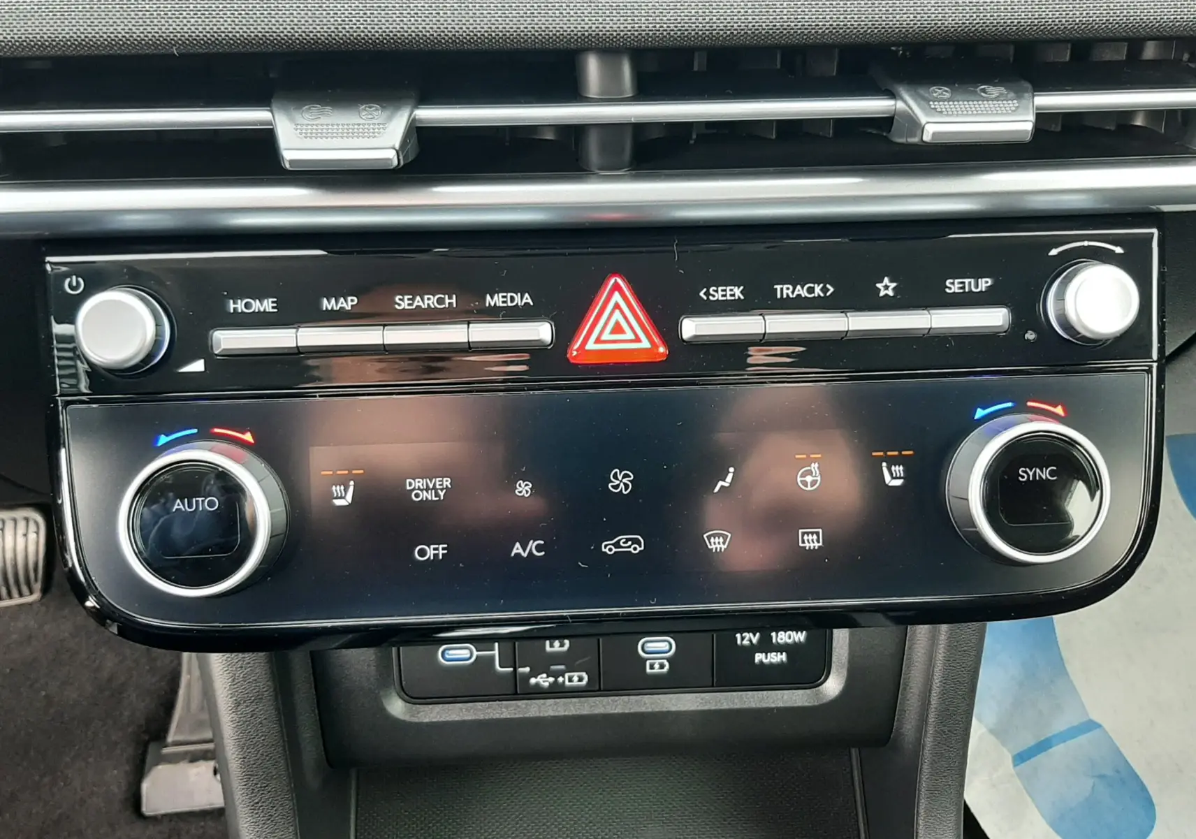 Vue rapprochée de la console centrale du Hyundai Tucson 2025 en gris Ecotronic, avec commandes climatisation et multimédia.