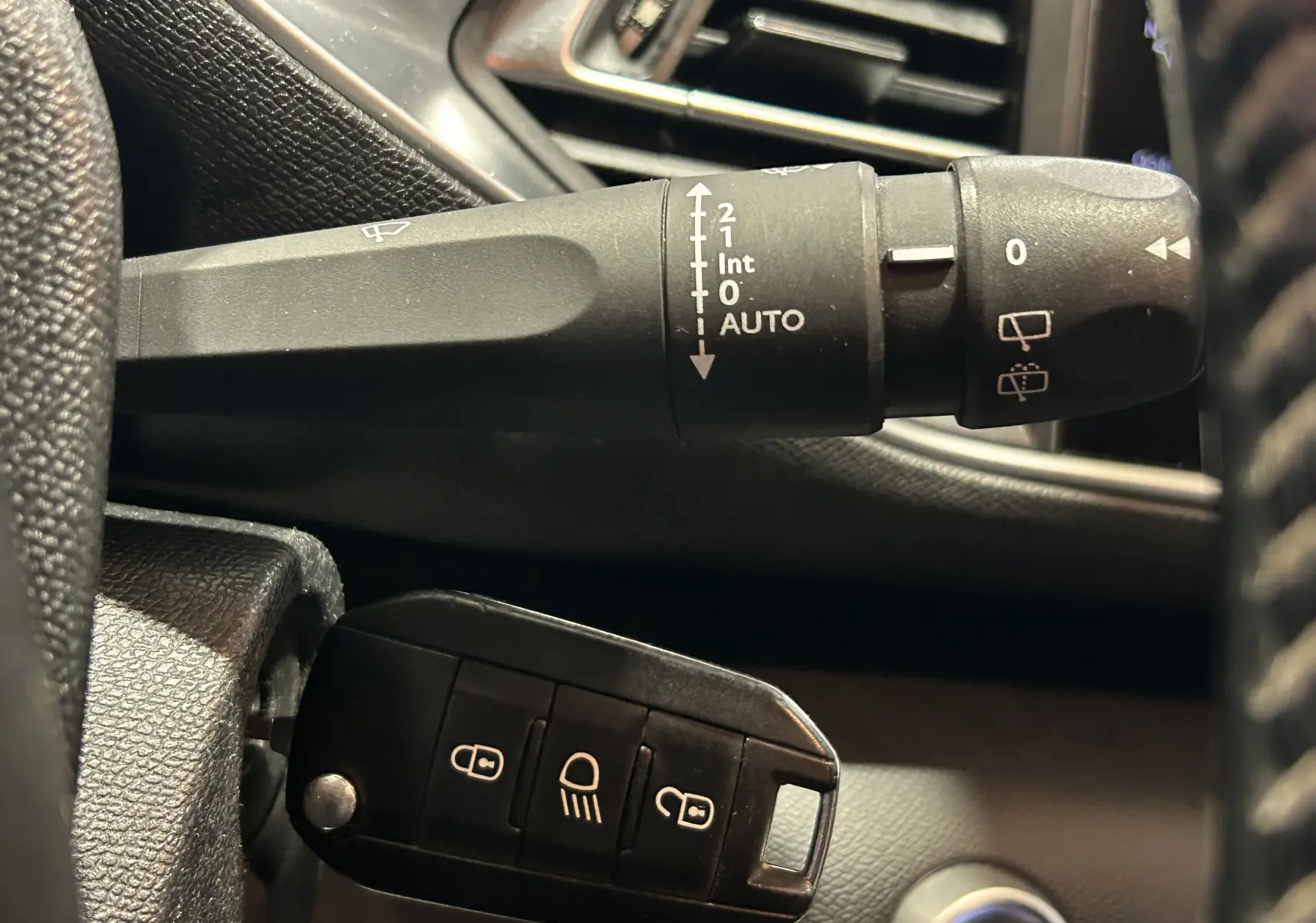 Gros plan sur la commande d’essuie-glace et la clé noire dans l’habitacle d’une Peugeot 308 SW noire de 2018.