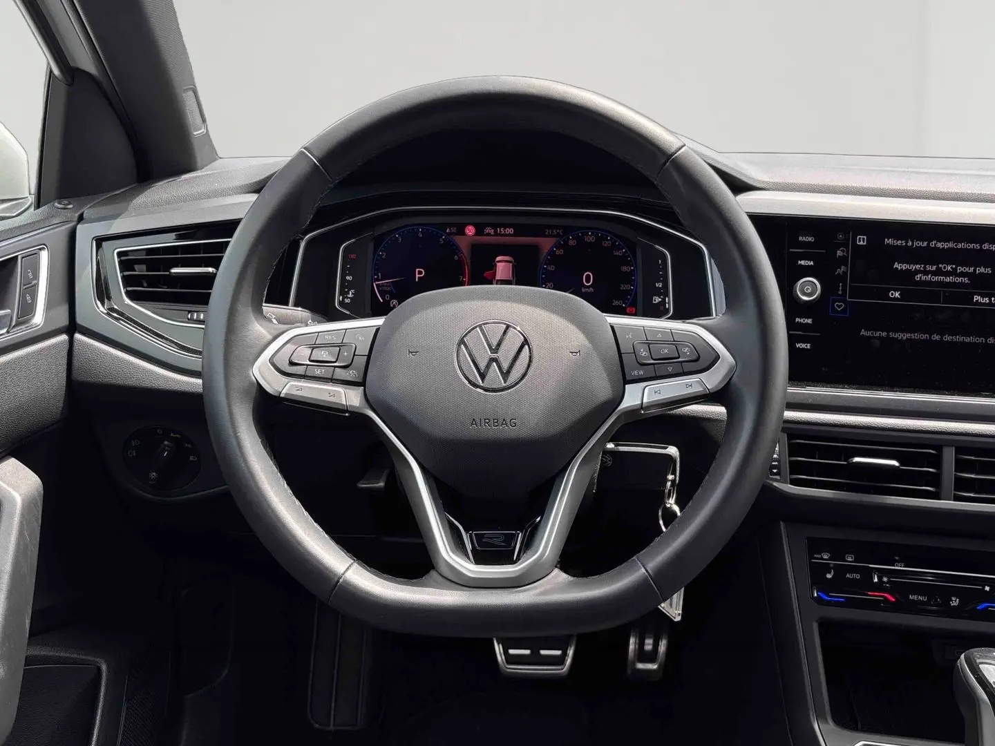 Vue frontale du volant cuir multifonctions du Volkswagen Taigo blanc, avec tableau de bord digital et écran tactile central.