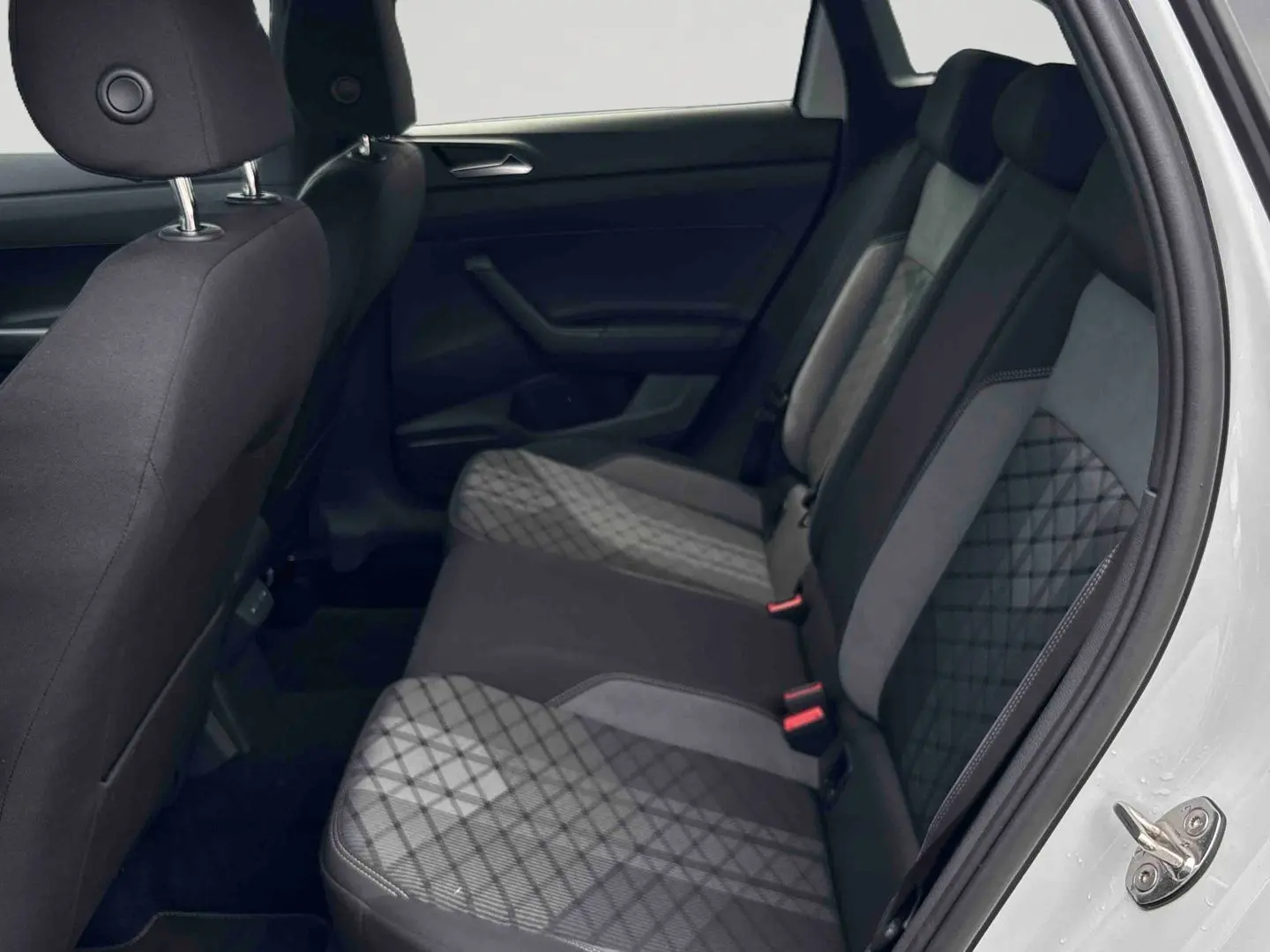 Vue intérieure côté droit des sièges arrière en tissu gris et noir du Volkswagen Taigo blanc, avec porte ouverte.