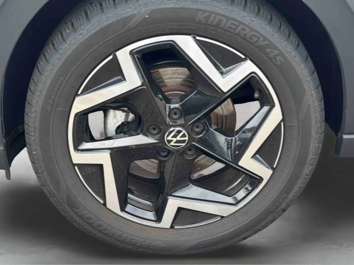 Gros plan sur la jante alliage noir et argentée 17 pouces du Volkswagen Taigo blanc, avec logo VW au centre.