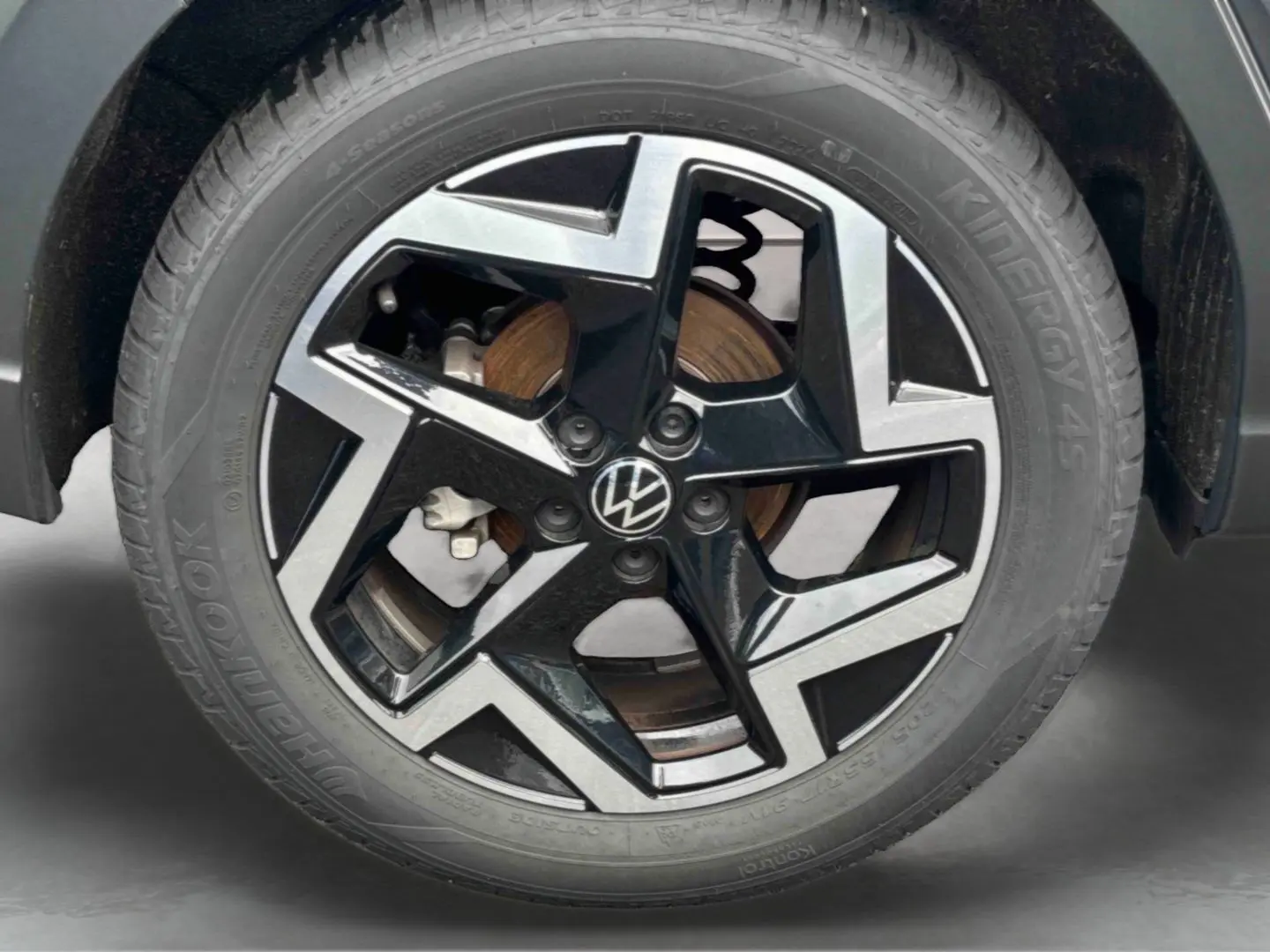Gros plan sur la jante alliage noir et argentée avec logo Volkswagen, roue avant droite du Volkswagen Taigo blanc.