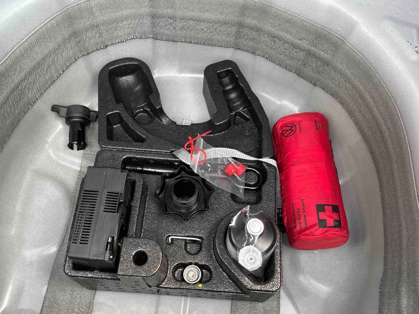 Gros plan sur le coffre à outils et trousse de secours rouge du Volkswagen Taigo blanc, vue de dessus.