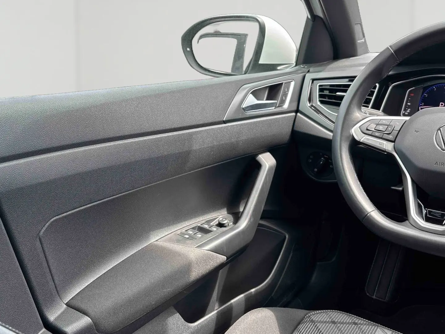 Vue intérieure côté conducteur du Volkswagen Taigo 2025, montrant la portière noire et le volant cuir multifonctions avec logo R-Line.