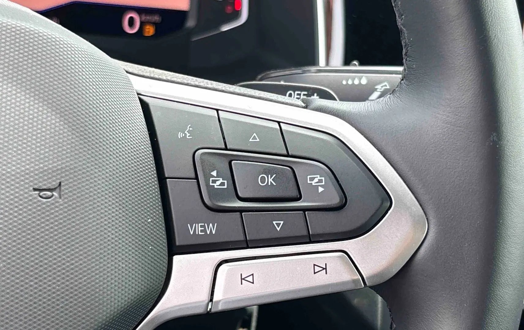Gros plan sur les commandes multifonctions du volant cuir noir du Volkswagen Taigo 2025, côté gauche.