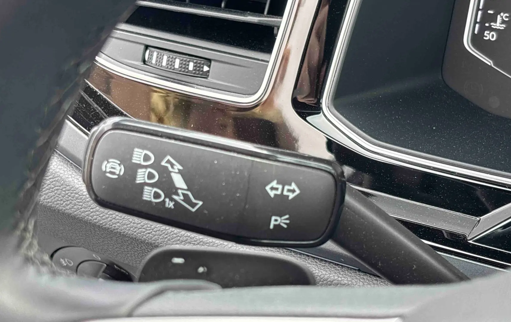 Gros plan sur la manette de clignotant et feux du Volkswagen Taigo 2025, intérieur noir avec détails chromés.