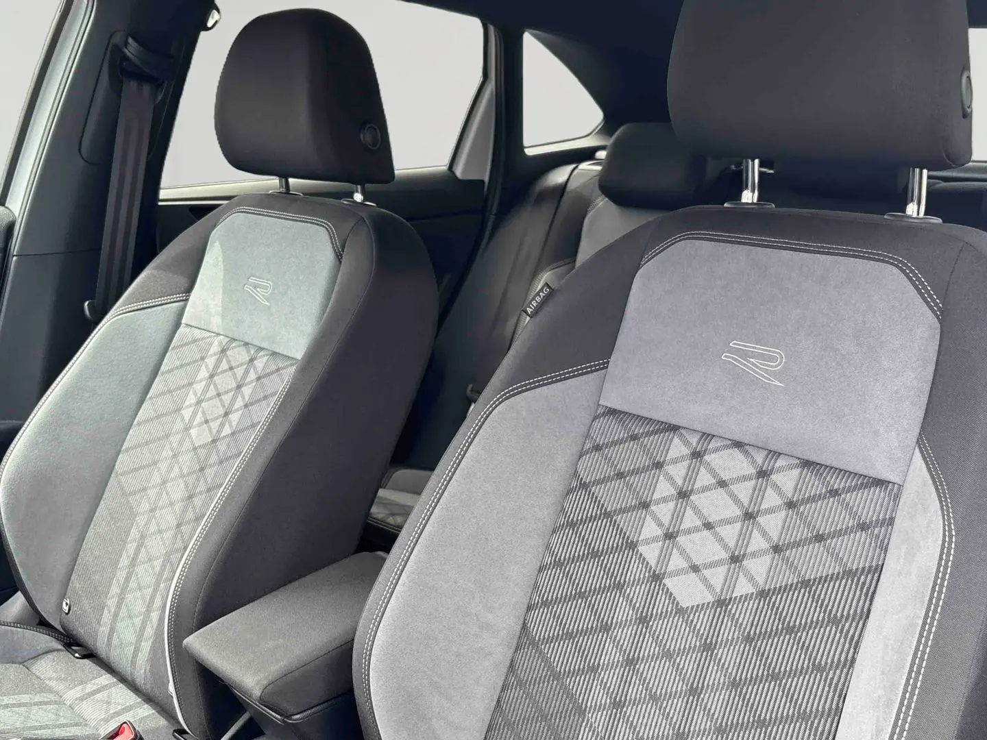 Gros plan sur les sièges avant gris et noirs avec logo R-Line brodé, intérieur du Volkswagen Taigo 2025.